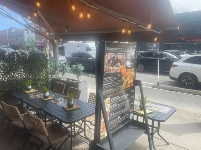 Casa Manila's Danforth patio at midday — set tables under the awning, menu board out front